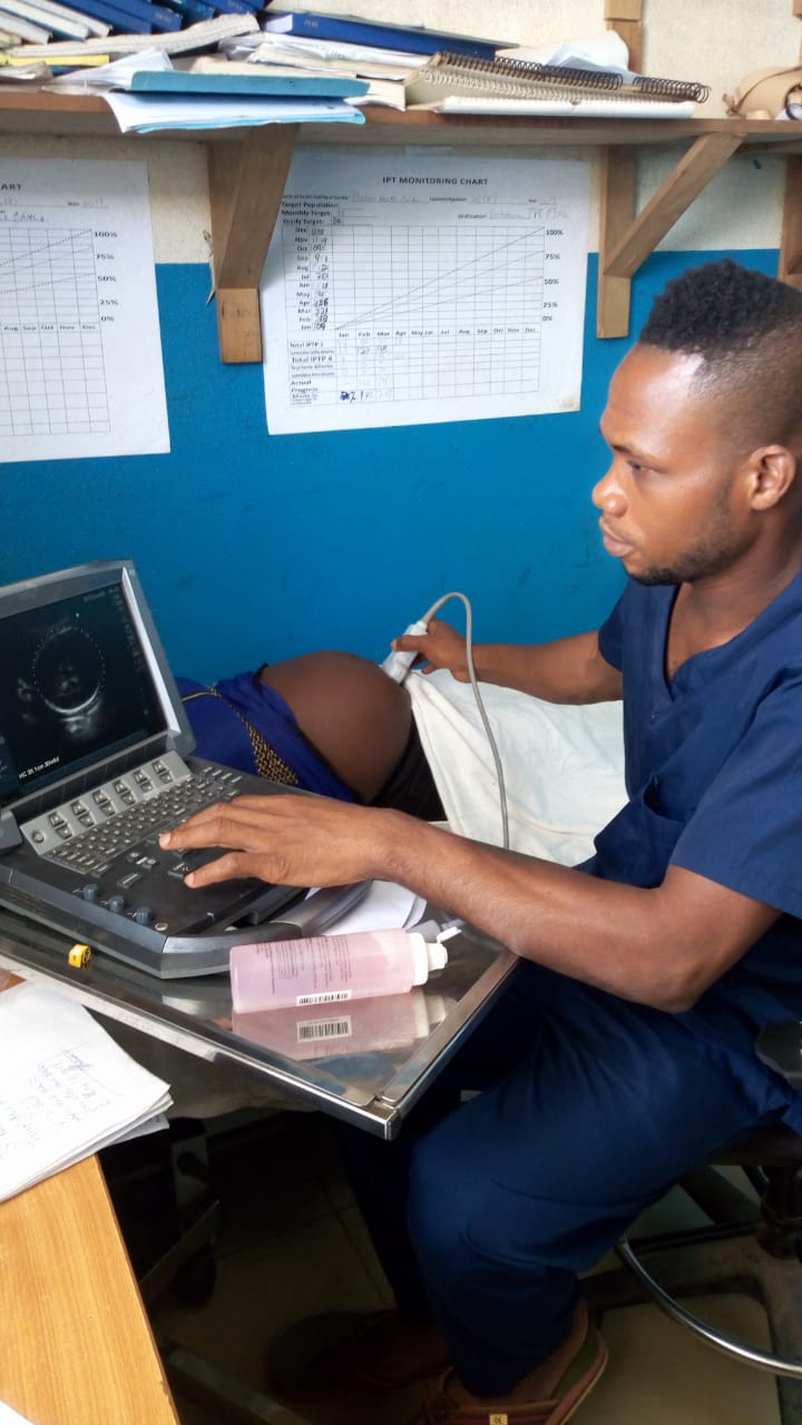 male nurse midwife performs ultrasound for pregnant patient at clinic in Liberia