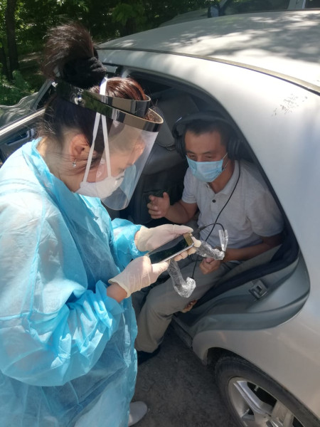 Dr. Merey Otepbergenova conducts a hearing test with a patient in her car