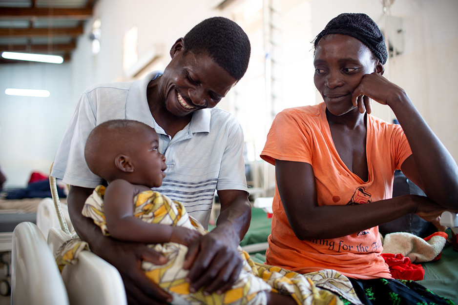 Chisomo Tigone, 7 months, sits with parents Flora and Thomas Tigone during his treatment for severe malaria. Despite the family's use of bug nets, this is their second case of childhood malaria in a month.
