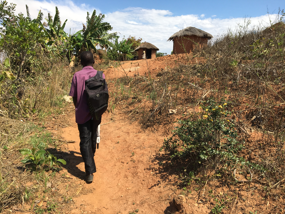 Health worker Silvester Dambe walks to Keredonia Wilfred's home