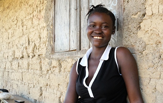 Fanta sits outside her home in Sierra Leone, where she lives with her son, John.