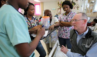 Dr. Paul Farmer consults on a potential HIV case with clinicians and nurses at the Hôpital Universitaire de Mirebalais in Mirebalais, Haiti, in 2016.