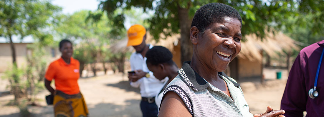 Rhoda Simba, a friend and fellow CHW, warmly greets the home visit group as they walk back to the PIH vehicle. 