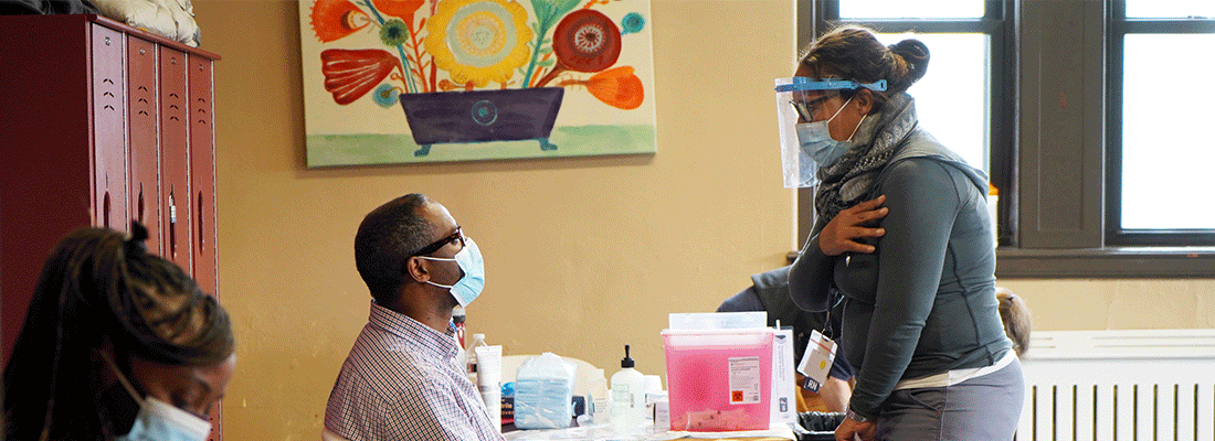 woman with mask on looking at a man sitting at a tabl