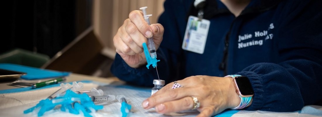 A public health nurses prepares doses of a COVID-19 vaccine during vaccination efforts in New Bedford, Mass. 