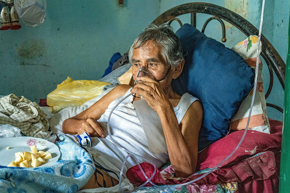 Leoncio Carrión in bed breathing with the support of medical oxygen; he is one of hundreds of patients who accessed lifesaving oxygen therapy through oxygen plant repairs by Socios En Salud, as Partners In Health is known in Peru.