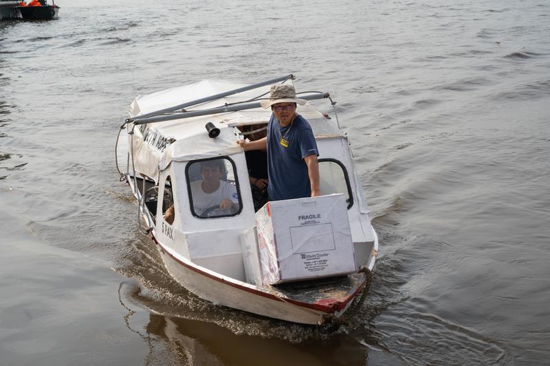 Socios En Salud staff transport TB equipment on a small boat in the Amazon river basin.