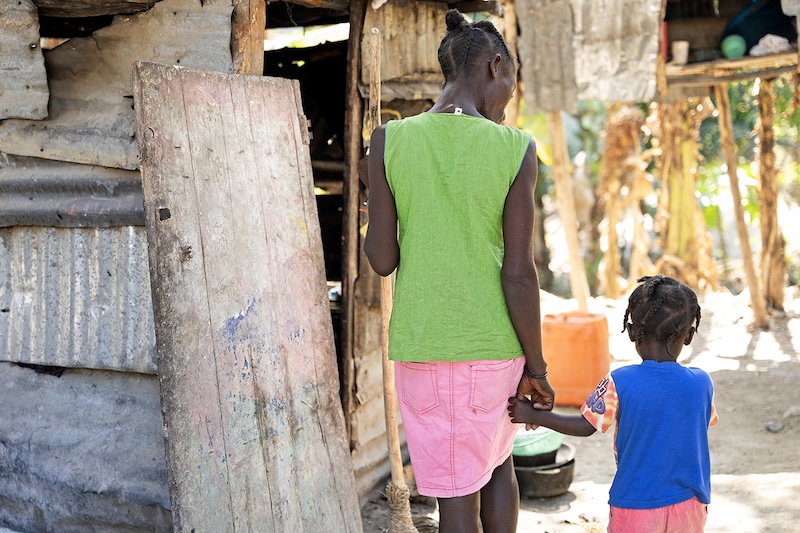 A mother and her child walk near their home during a malnutrition visit in Haiti