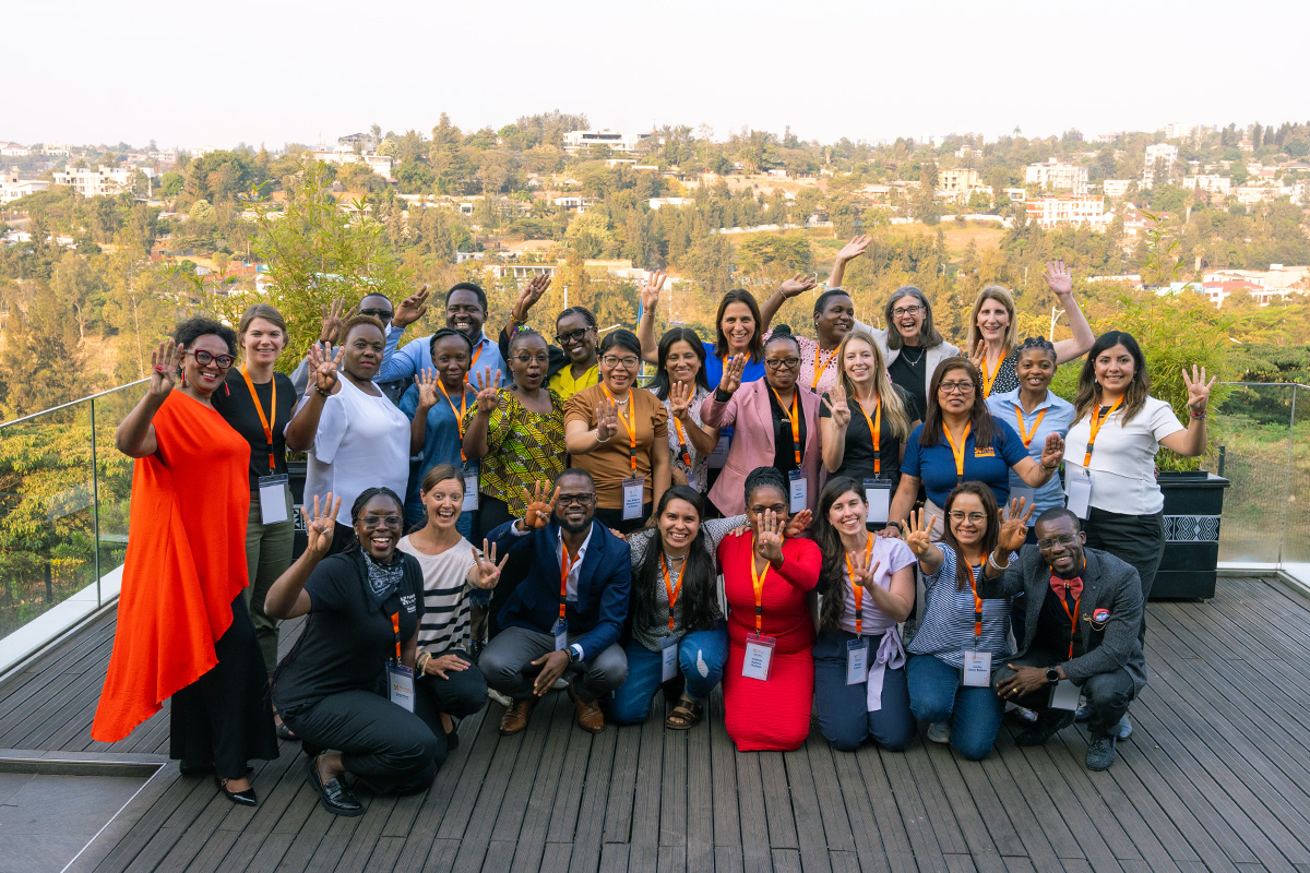The fourth cohort of Global Nurse Executive Fellowship members smile and wave in a group during a weeklong intensive in Rwanda.