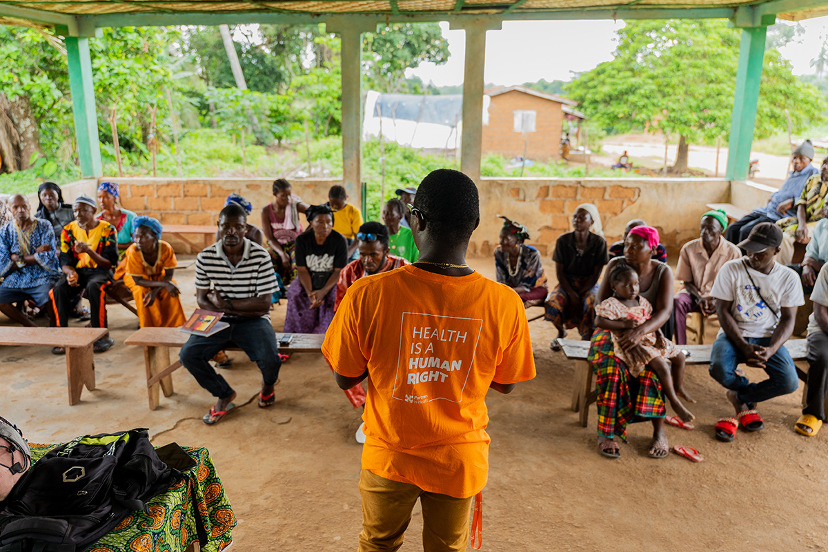 Person with their back to the camera is wearing an orange shirt that says "health is a human right"