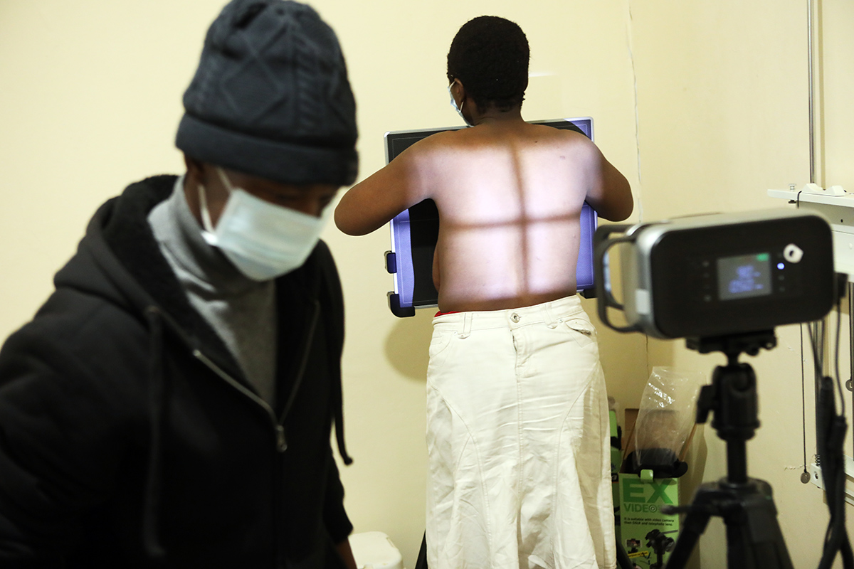 Tsepo Tamorene helps a patient receive an X-ray with the new portable x-ray machine at Lebakeng at PIH-supported Lebakeng Health Center.