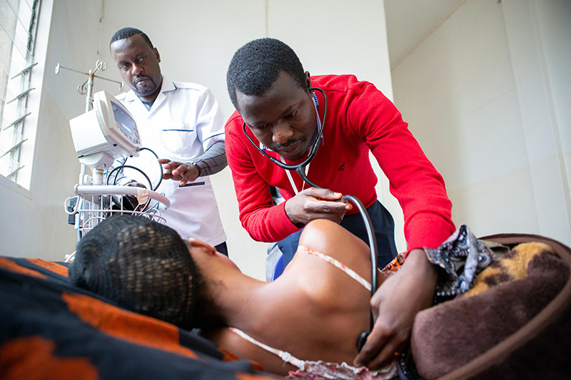 Nurse John Paul (left) and Dr. George Talama (right) check on a recently diagnosed 27-year-old HIV patient at Neno District Hospital. 