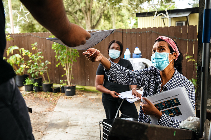community health worker provides COVID-19 information at neighbohood homes in Immokalee, Florida