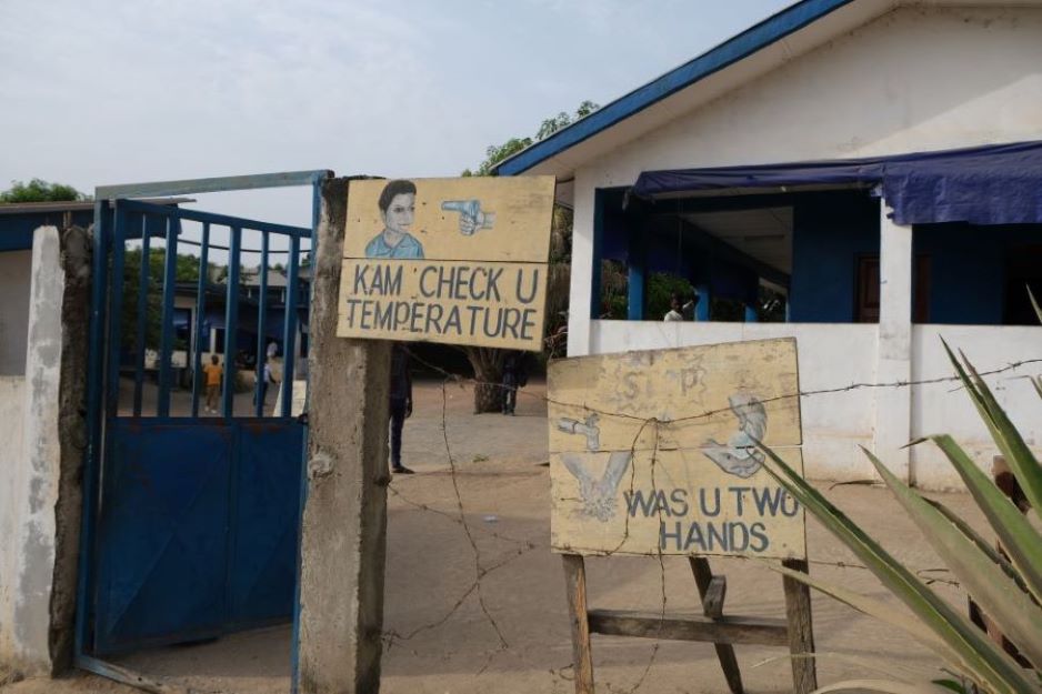 Signs at the entrance of PIH-supported Wellbody Clinic  tell patients in Krio to wash their hands and get their temperature checked upon entering the facility. Photo by Maya Brownstein / Partners In Health