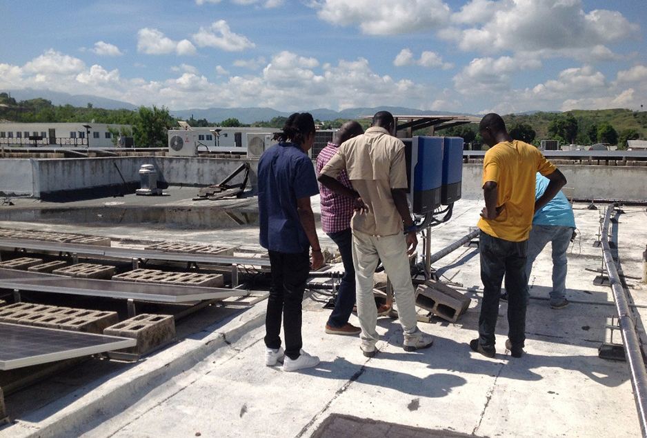 Facilities staff anchor a communications antenna on the roof of University Hospital in Mirebalais, Haiti, in preparation for Hurricane Irma. Photo by Neilsen Fleuristal / Partners In Health 