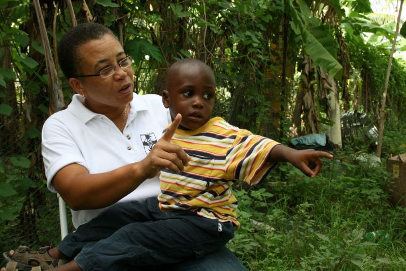 Loune Viaud sits with young boy during home visit in Haiti