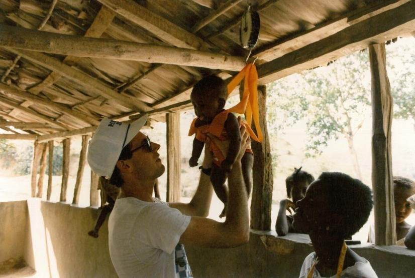 Paul Farmer holding the infant of one of his first patients in Haiti