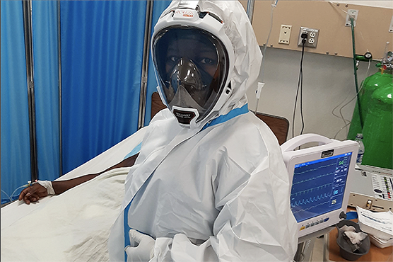 Dr. Benoucheca Pierre in full personal protective equipment stands at the bedside of a critically ill COVID-19 patient in the intensive care unit at University Hospital Mirebalais Haiti.