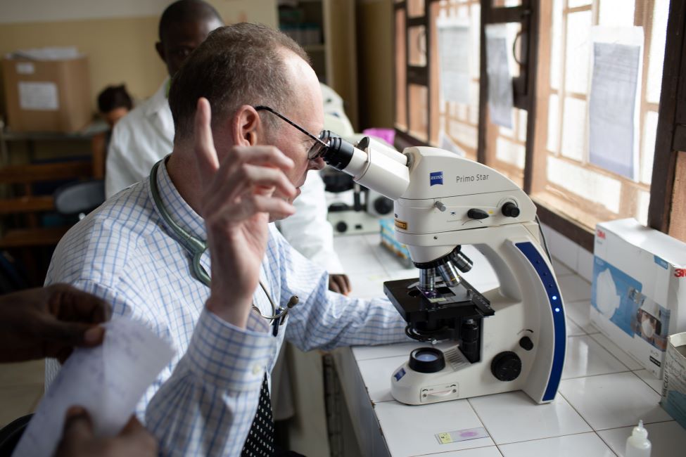 Dr. Farmer examines Issa's specimens through a microscope