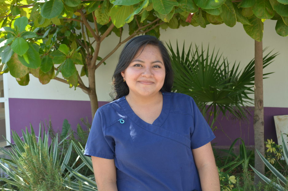 Adriana Fabián, a midwife at Casa Materna, stands outside in blue scrubs and smiles.