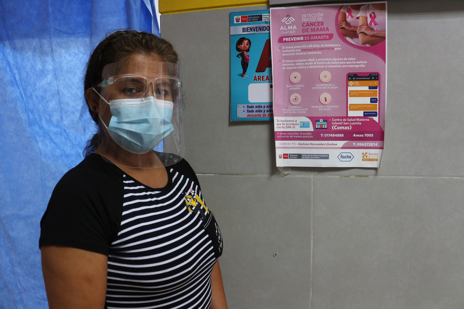 A patient stands next to a poster with information about breast cancer.
