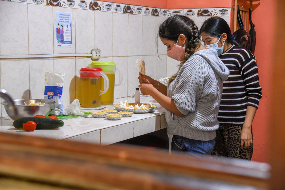 A resident of the safe house practices baking skills under the supervision of a community health worker. Photo by Julio Medina for SES.