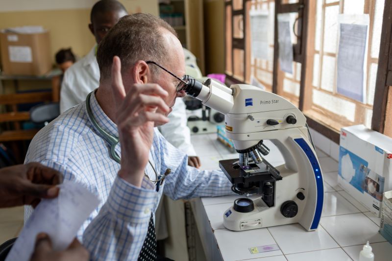 Paul Farmer views a lab sample under a microscope in Sierra Leone