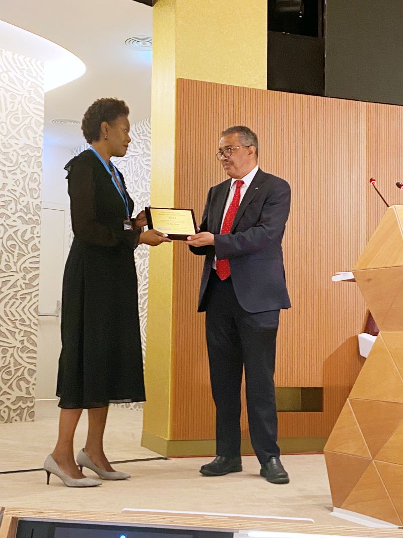 Didi Bertrand accepts the WHO award from Dr. Tedros Adhanom Ghebreyesus