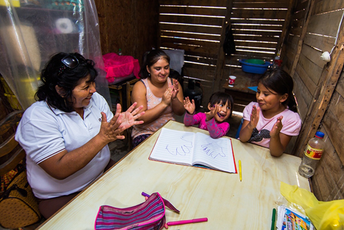 Community health worker Inela Espinoza teaches educational games to a family in their home.