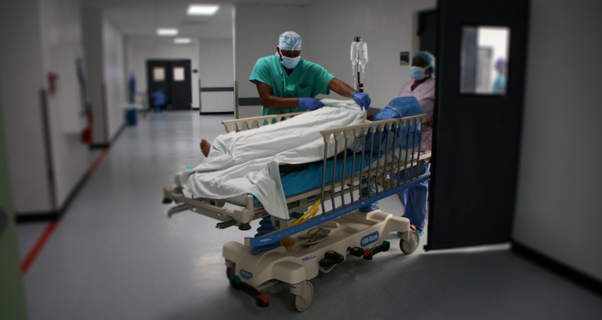 Dr. Christophe Milien wheels a patient into a room after surgery at University Hospital in Mirebalais, Haiti,
