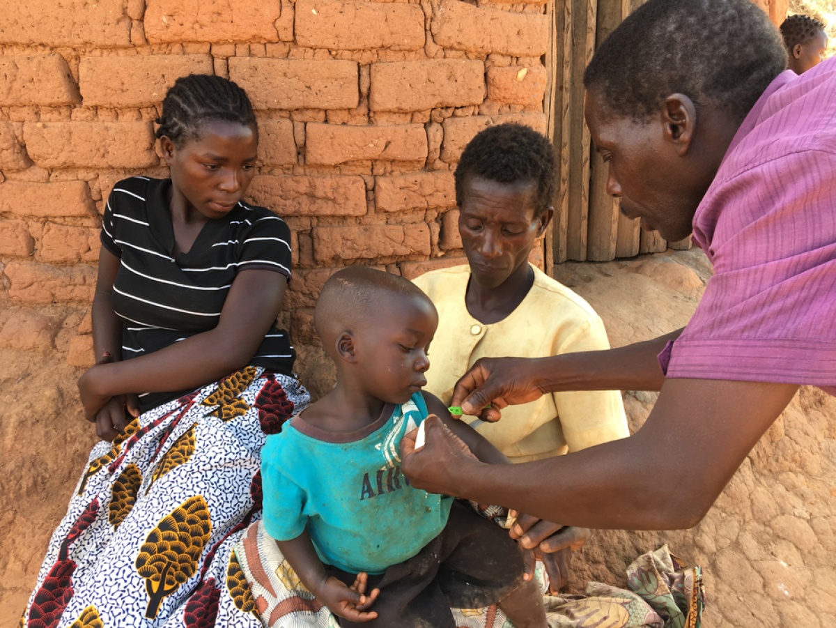 Senior CHw Silvester Dambe, right, tests a toddler for malnutrition