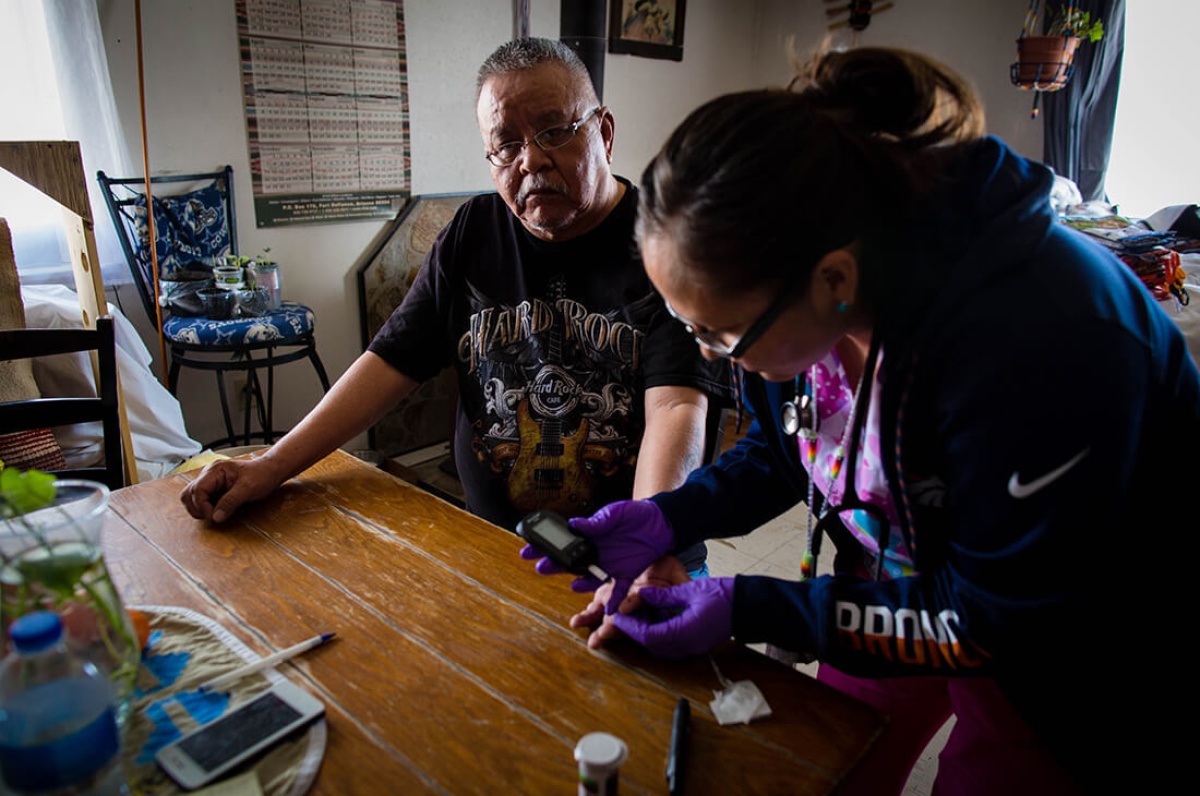 A community health worker in Navajo Nation checks a patient's blood sugar.