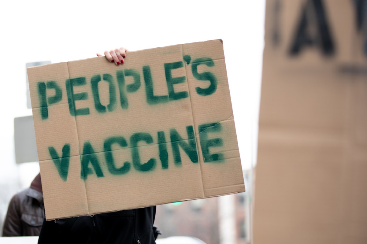 A protester holds a sign that says People's Vaccine