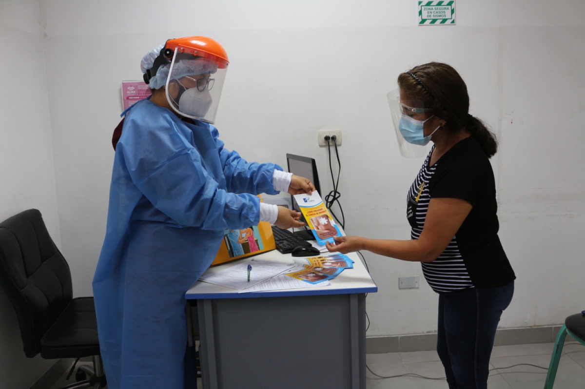 A doctor in personal protective equipment gives a patient information about breast cancer.