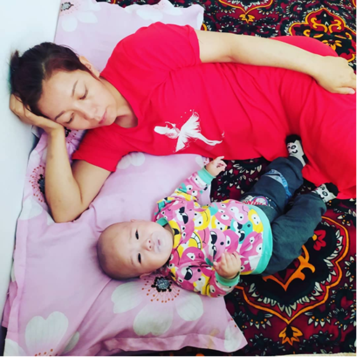 Maral Shorayeva laying down with her infant daughter