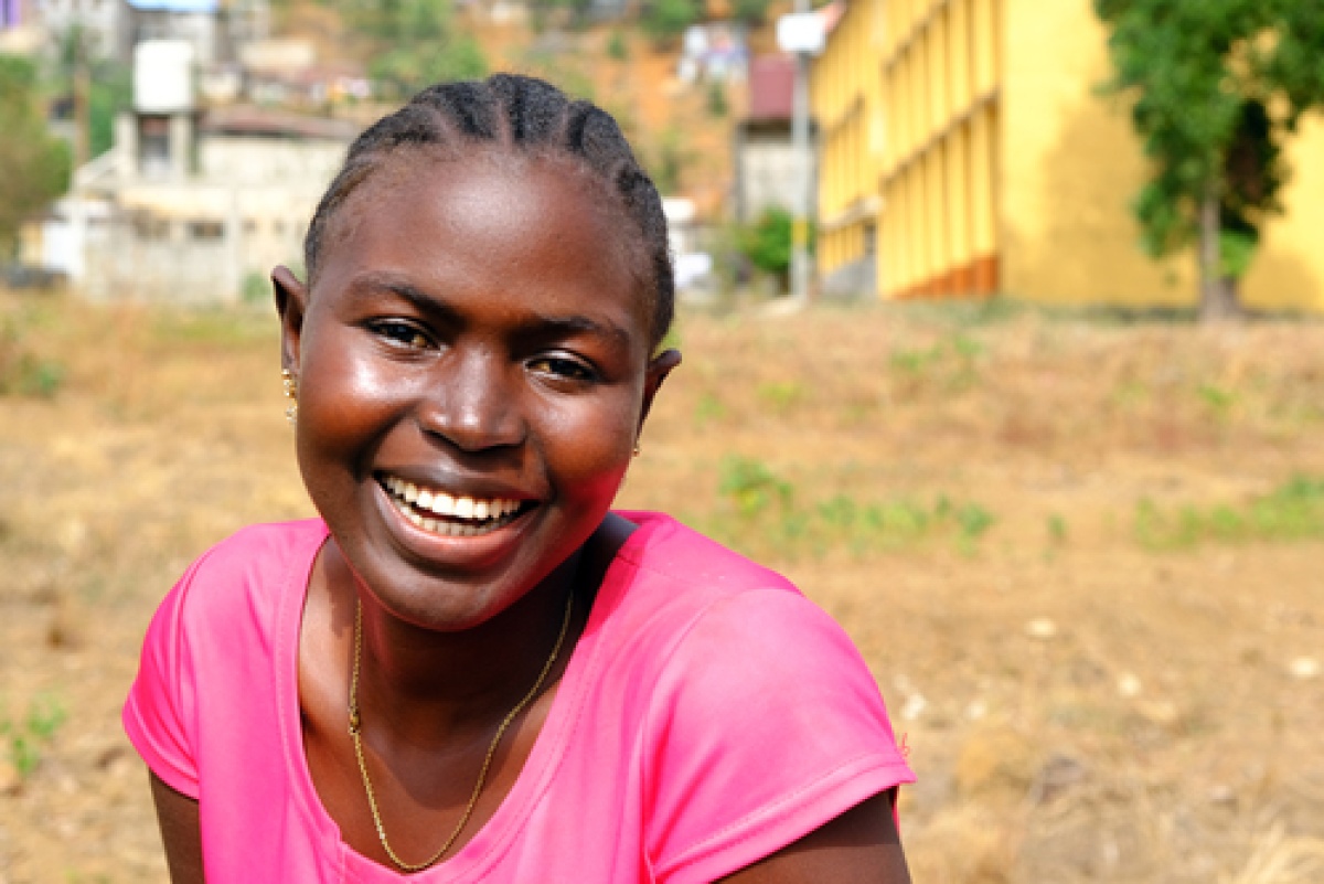 Saffiatu Sesay received care for tuberculosis at Lakka Government Hospital in Sierra Leone. She smiles for the camera and wears a pink shirt.