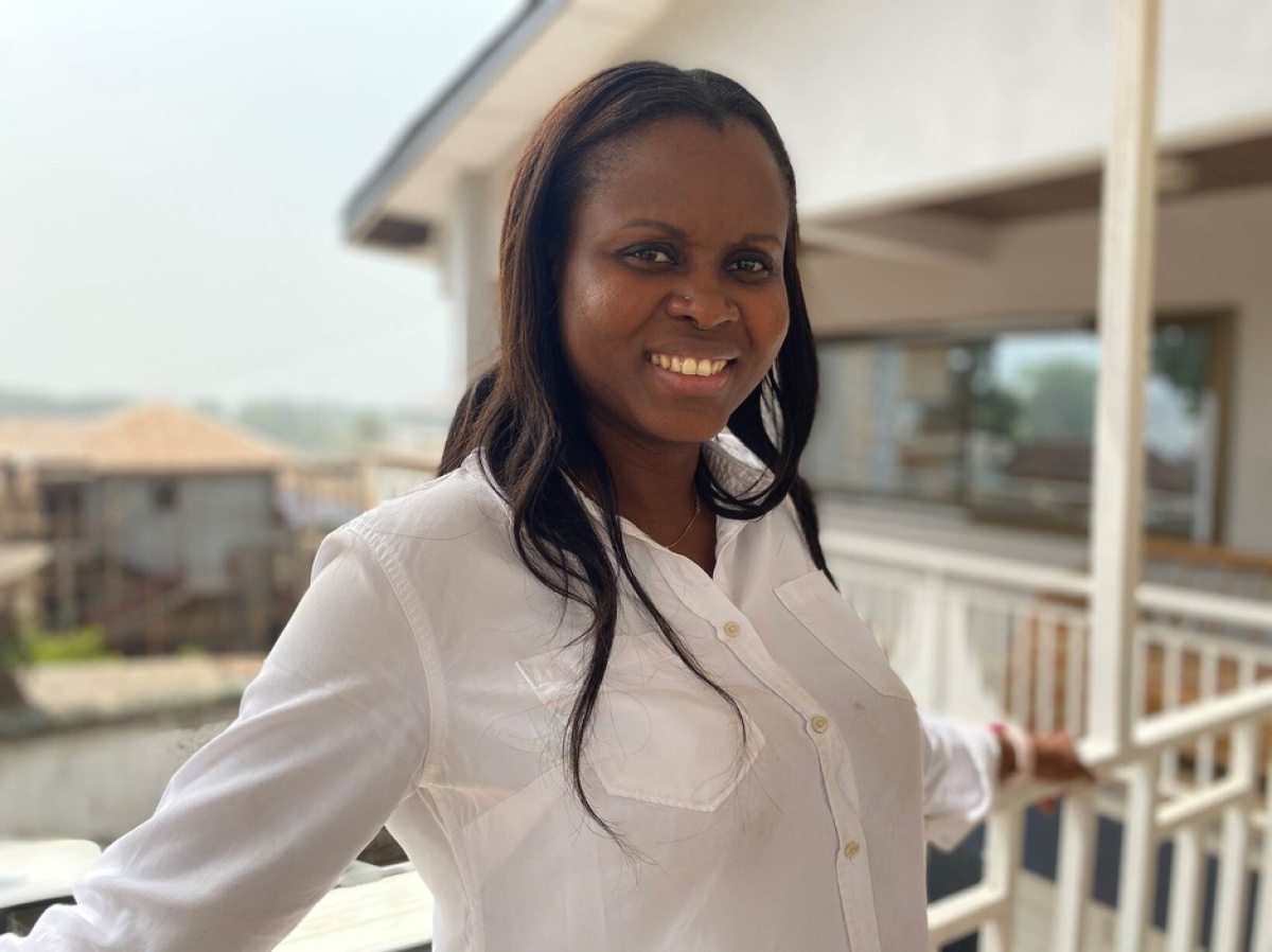 Vicky Reed, director of nursing for PIH Sierra Leone, poses for a photo in a white shirt on a balcony.