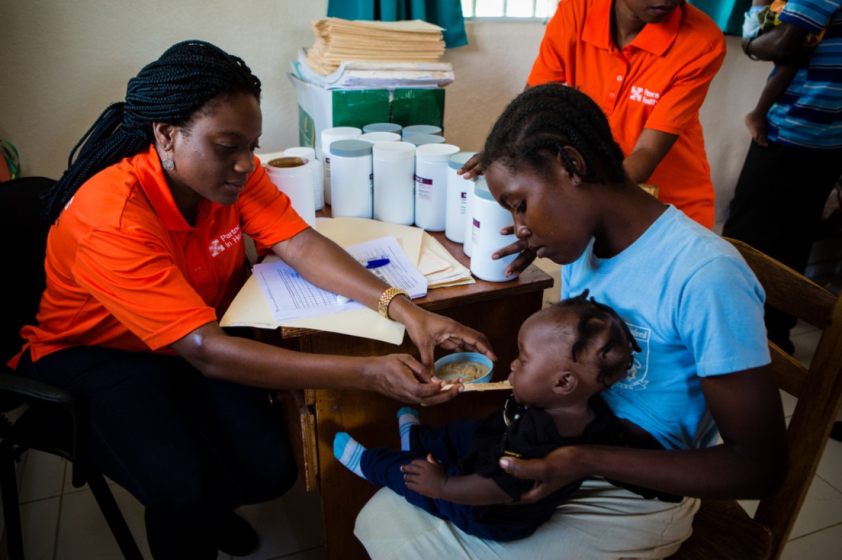 Ms. Esther Mahotiere, a nutrition program coordinator in Haiti, feeds Nourimanba to 8-month-old Wisline Sauvene at the malnutrition clinic in Boucan Carré.