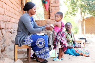 Community Health Worker Annie Jere visits with Milica Steven and her three children at their home in Neno, Malawi, screening the family for health concerns.