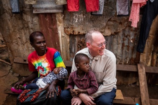 Dr. Paul Farmer smiling and sitting with a child sitting in his lap