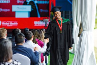 Graduate Heritier Mfura, class representative for the inaugural MBBS-MGHD cohort, fist bumps an audience member.