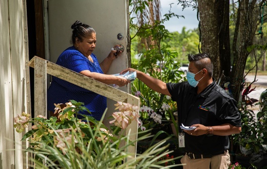 Osman López Hernández, from the Healthcare Network, speaks with Maria Escutia at her home about the Covid-19 vaccination along with offering masks, hand sanitizer and other helpful medical information in Immokalee, FL