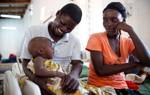 Chisomo Tigone, 7 months, sits with parents Flora and Thomas Tigone during his treatment for severe malaria.