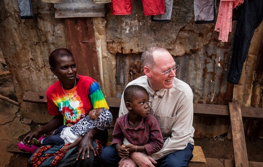 Dr. Paul Farmer smiling and sitting with a child sitting in his lap
