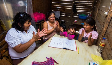 Project CASITA home visit Community health worker Inela Espinoza teaches educational games to a family in their home.