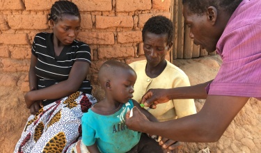 Senior CHw Silvester Dambe, right, tests a toddler for malnutrition