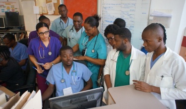 Haitian residents huddle around a computer