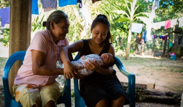 A Midife passes a new born to the awaiting mother