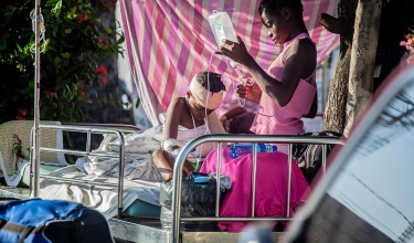 Woman gives IV to a boy on a hospital bed