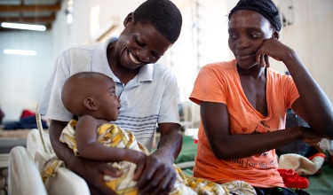 Chisomo Tigone, 7 months, sits with parents Flora and Thomas Tigone during his treatment for severe malaria.